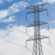 An electric tower and cables with a blue cloudy sky in the background