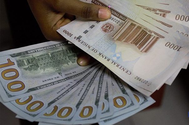 A hand holding 1000 Naira notes and 100 Dollar notes